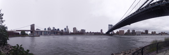 The Brooklyn and Manhattan Bridges cross the East Riven in this photo taken from DUMBO in Brooklyn, New York City after Hurricane Irene. In the background are the buildings One World Trade Center and New York By Gehry. The river was running strong with white caps due to the extra water from the storm.